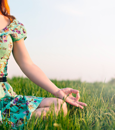 Concept de tranquillité et de bien être représenté par une femme assise dans l'herbe