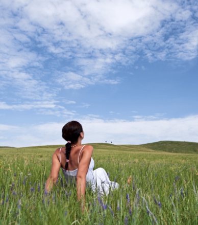 Relaxed woman lying on a flower field and watching the blue sky