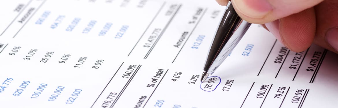 Close up shot of a man’s hand holding a pen and filling out a Tax Form