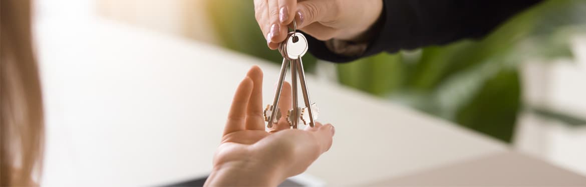 Agent immobilier remettant les clés d’une maison à un couple. Gros plan sur des mains masculines et féminines